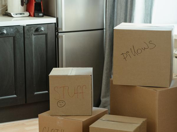 Cardboard moving boxes stacked on the floor of a bright kitchen